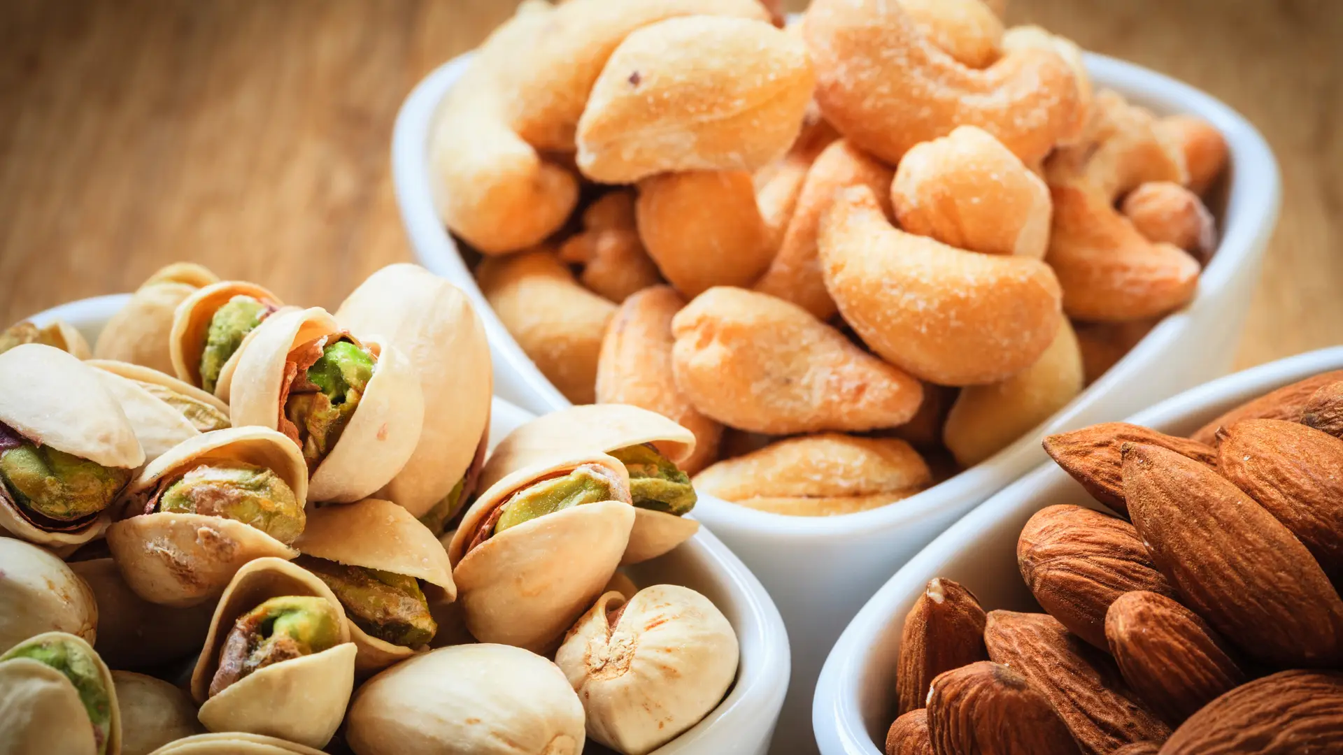 Processed cashews, almonds and pistachios in separate bowls